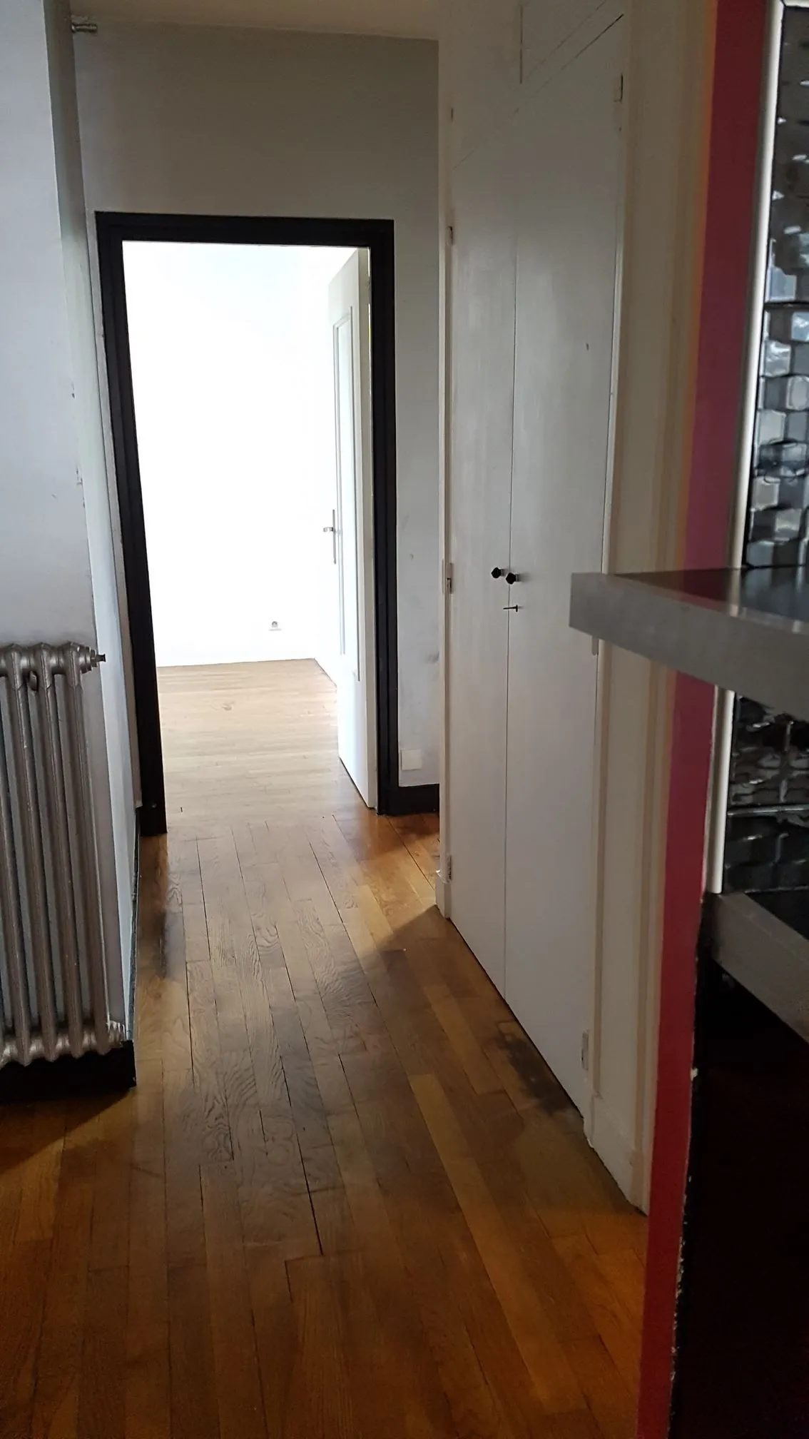 Couloir de l'appartement des Vaucelles avant travaux, parquet sombre et mur rouge