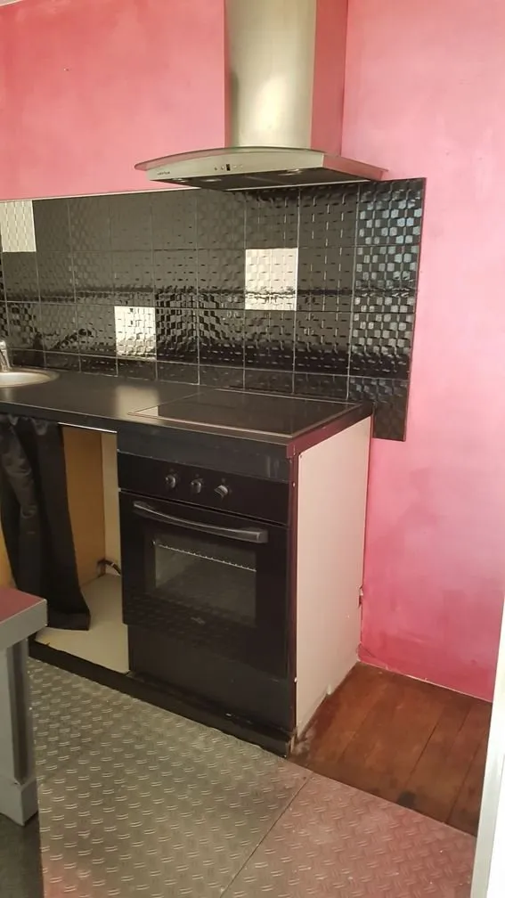 Cuisine de l'appartement des Vaucelles avant travaux, meubles noirs et mur rouge