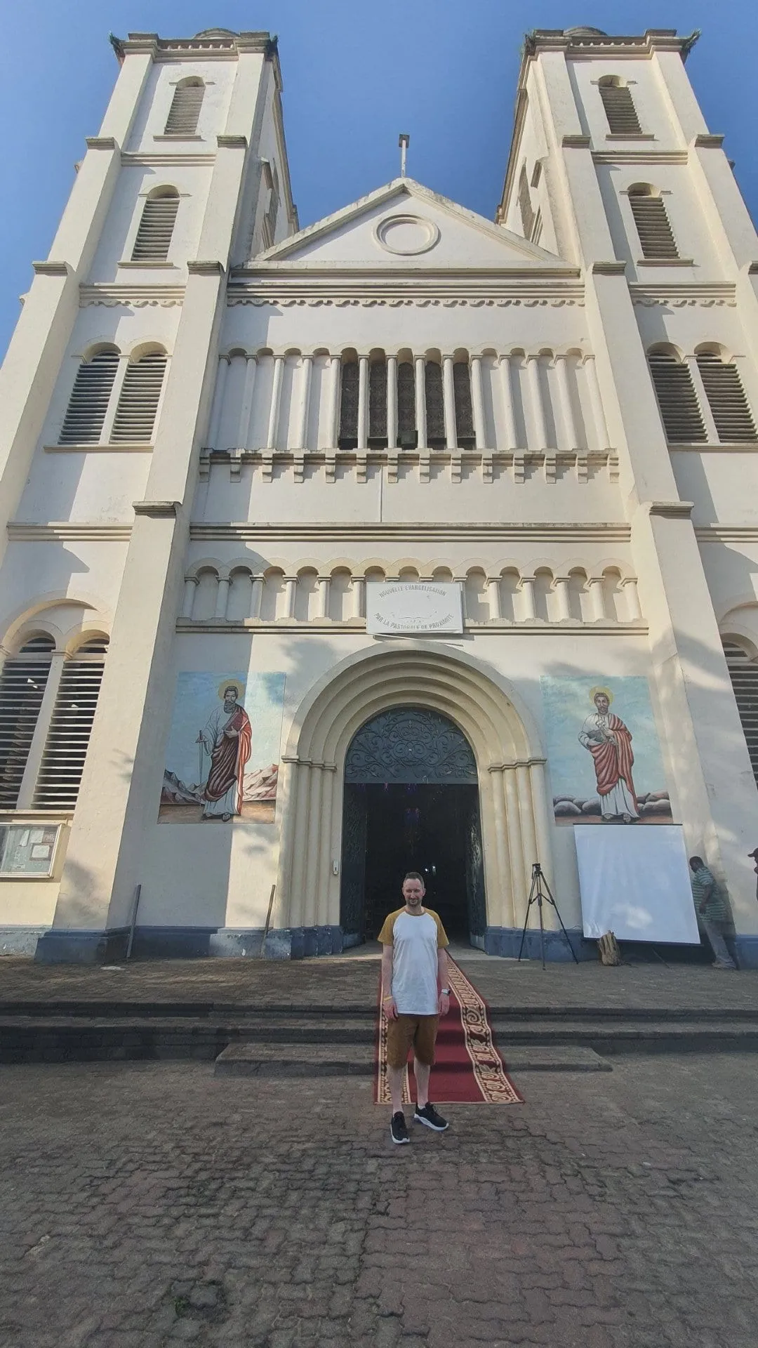 Un bâtiment ancien du centre de Douala, façade blanche à arcades et fronton, sous un ciel clair
