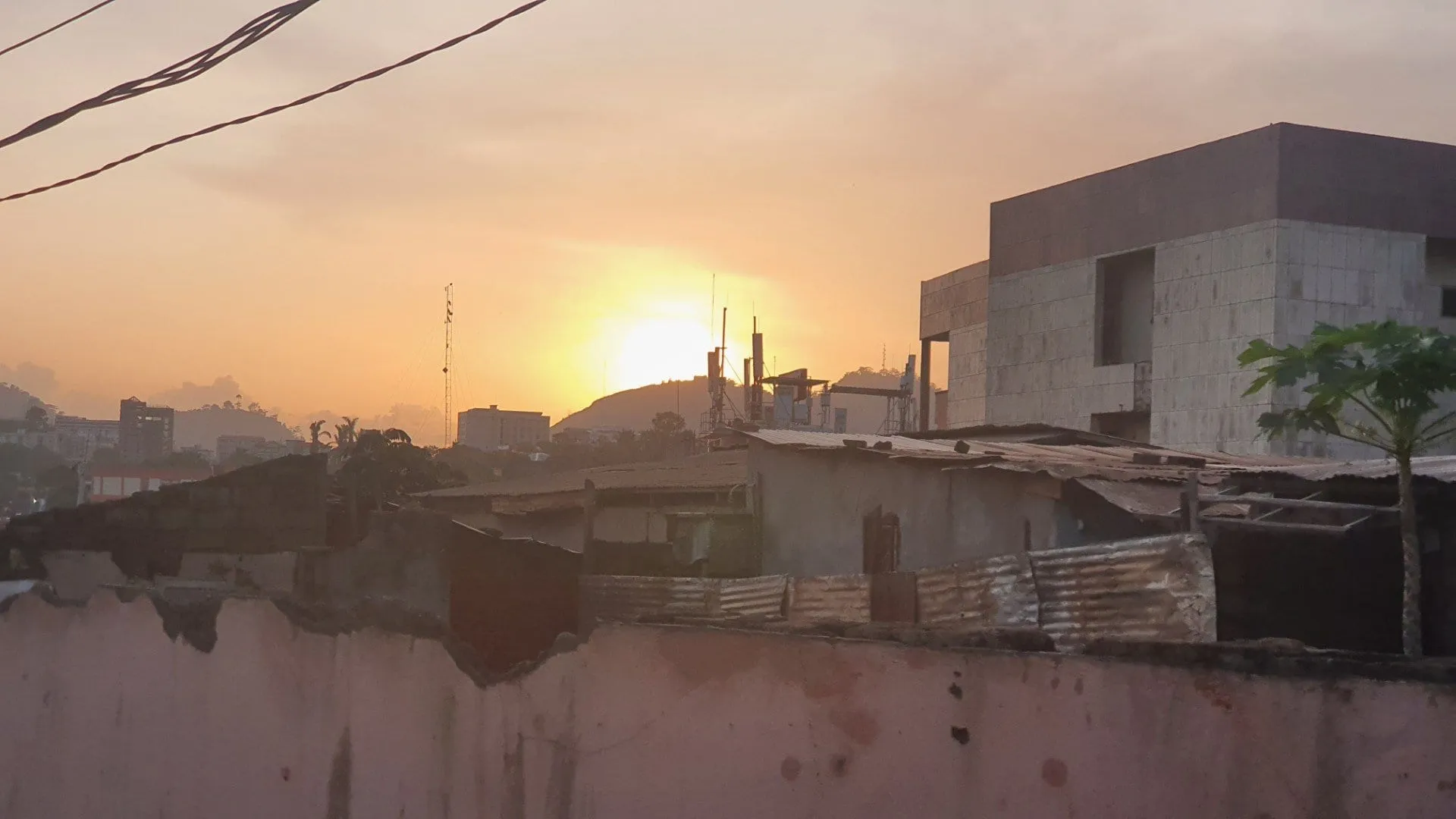 Le soleil se couchant sur les toits de tôle de Yaoundé, collines à l'horizon
