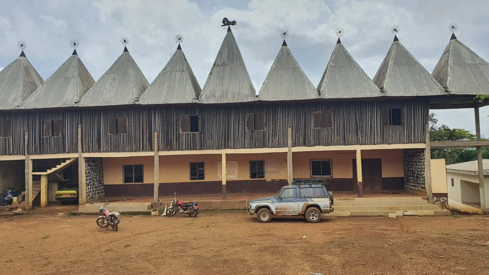 La façade d'une chefferie bamiléké, longue galerie surmontée d'une rangée de toits coniques