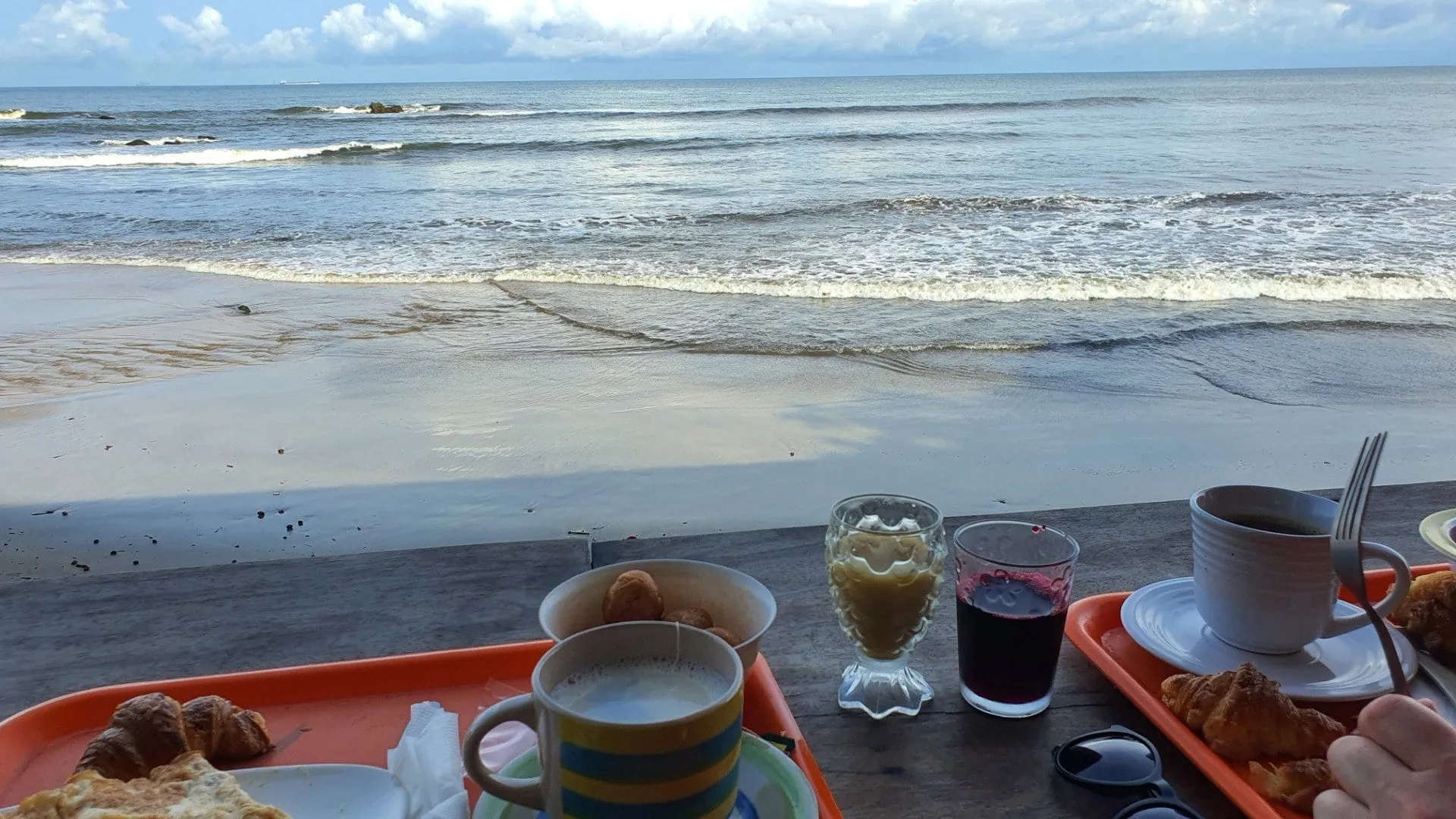 Un plateau de petit-déjeuner posé face à l'océan, la plage derrière