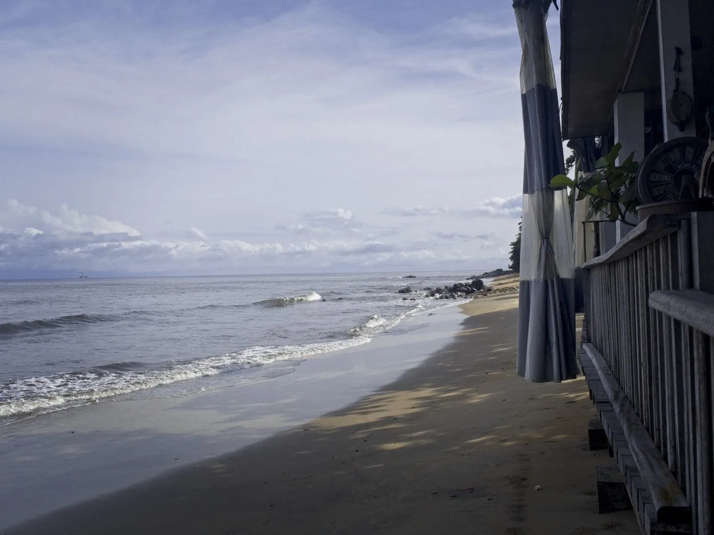 La plage de Kribi au petit matin, vue depuis l'intérieur d'un bâtiment, l'océan gris et calme