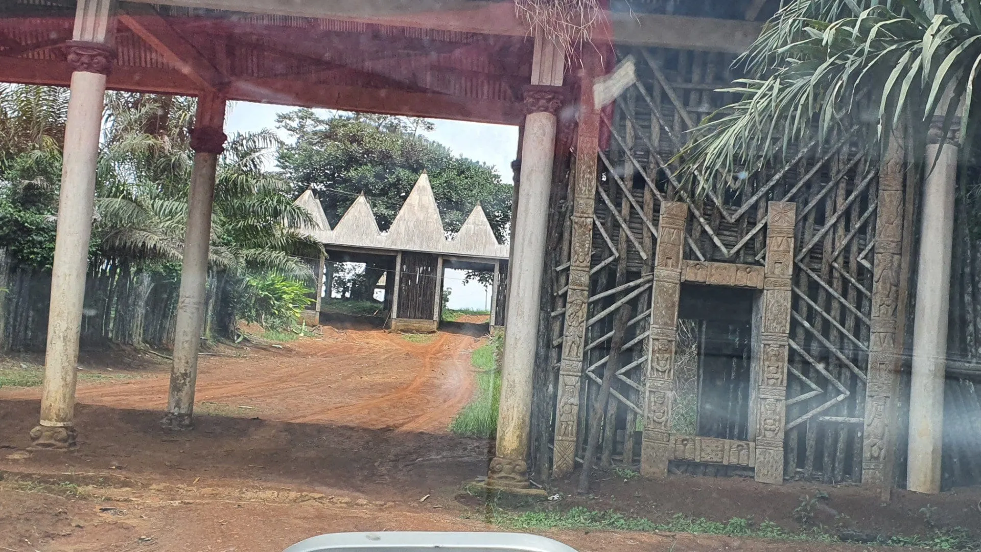 Portail monumental d'une chefferie bamiléké, surmonté de son toit conique, au bord de la route