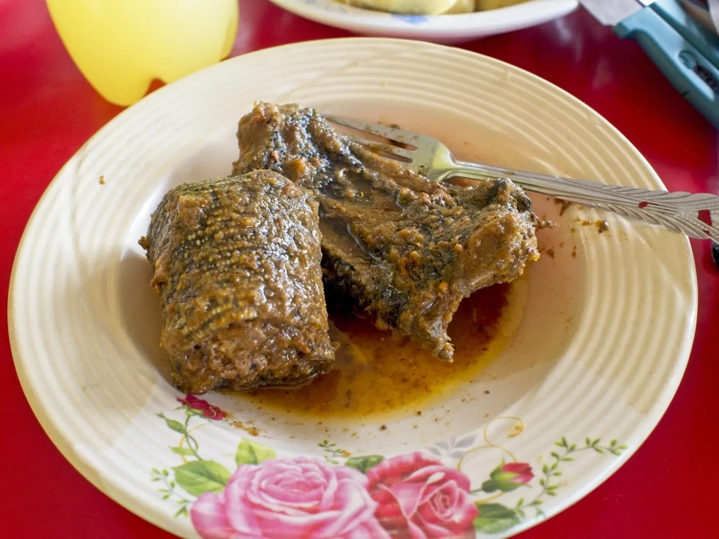Un morceau de viande braisée à la peau écailleuse, dans sa sauce, sur une assiette à motif de roses