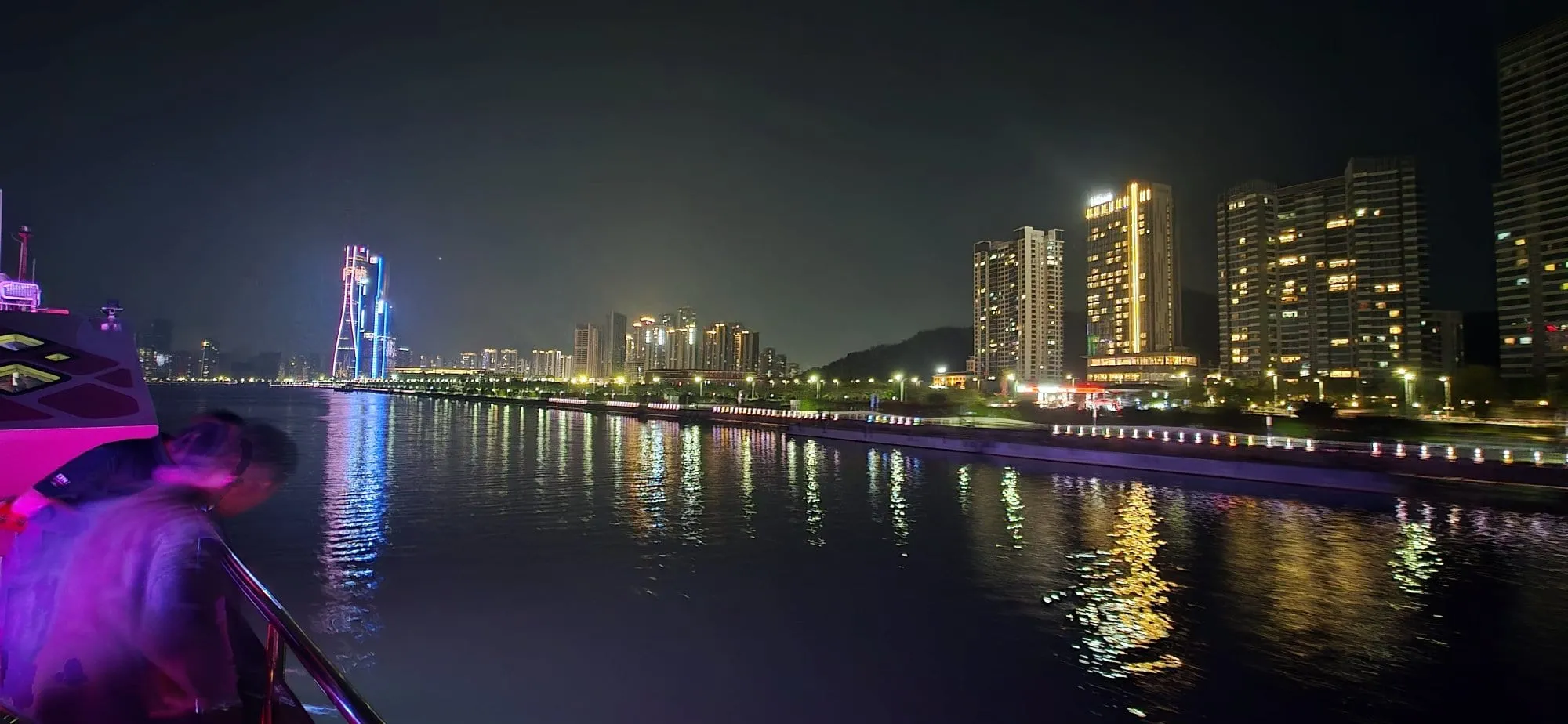 Une baie illuminée de tours et de lumières colorées, vue depuis la promenade