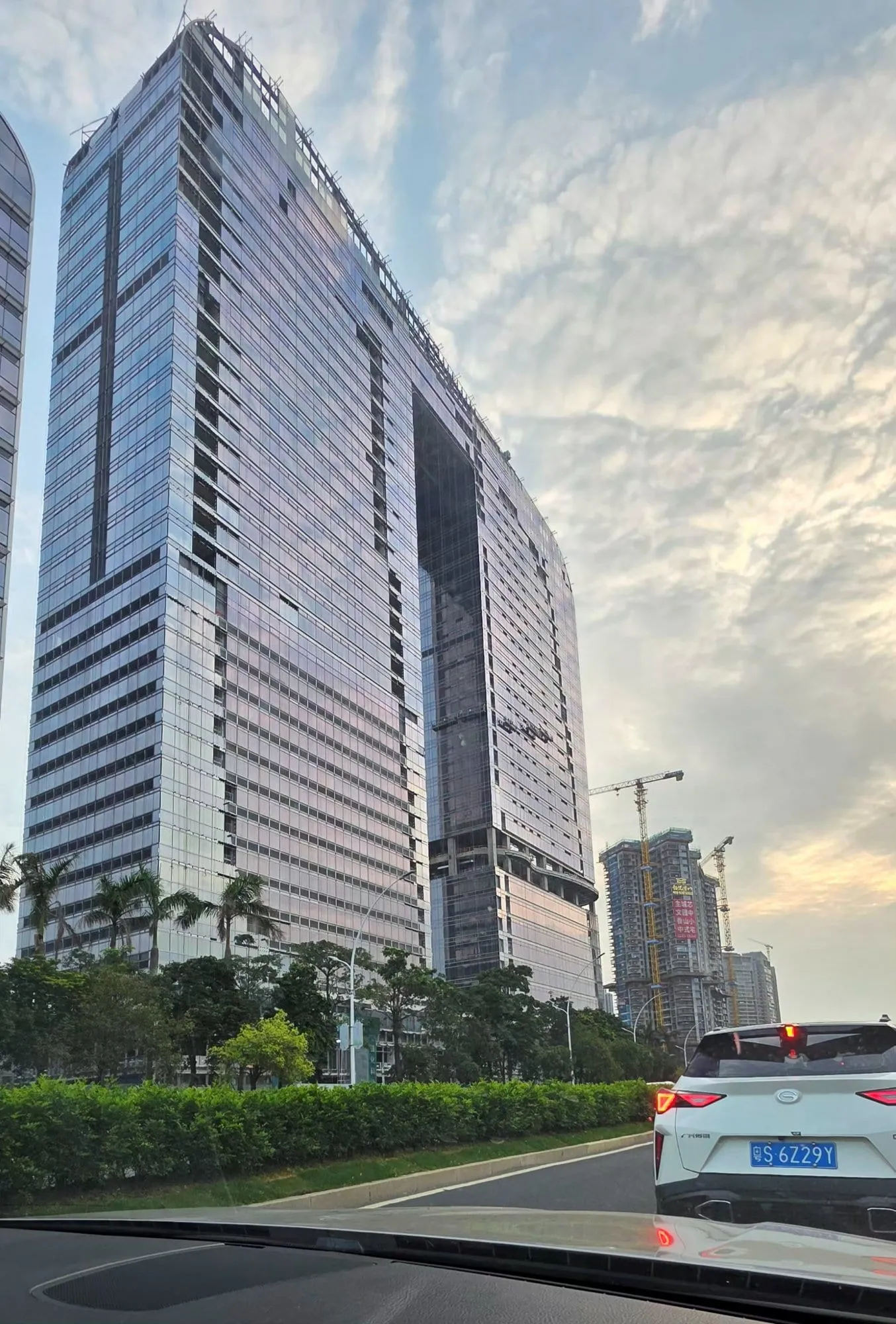 Des gratte-ciel de Shenzhen vus depuis la rue, façades de verre et grues au loin