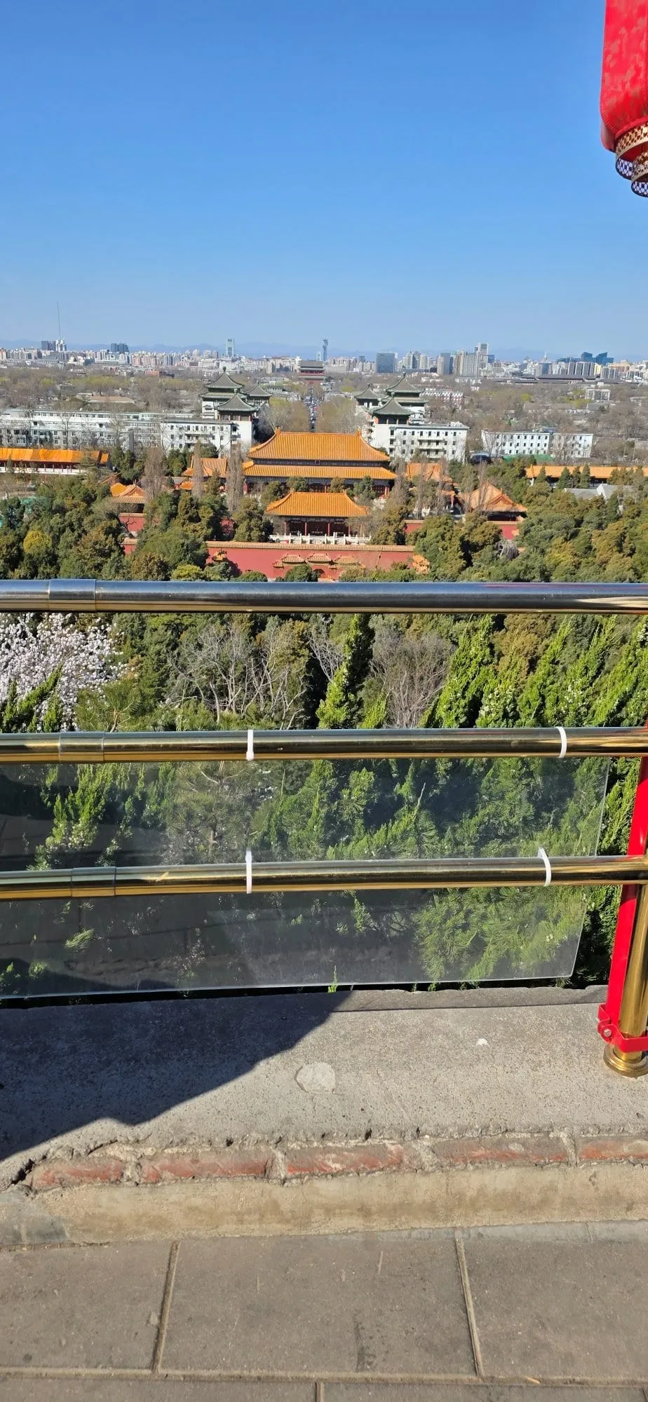 Les toits dorés de la Cité interdite au loin, vus depuis la terrasse du parc Jingshan, derrière un garde-corps