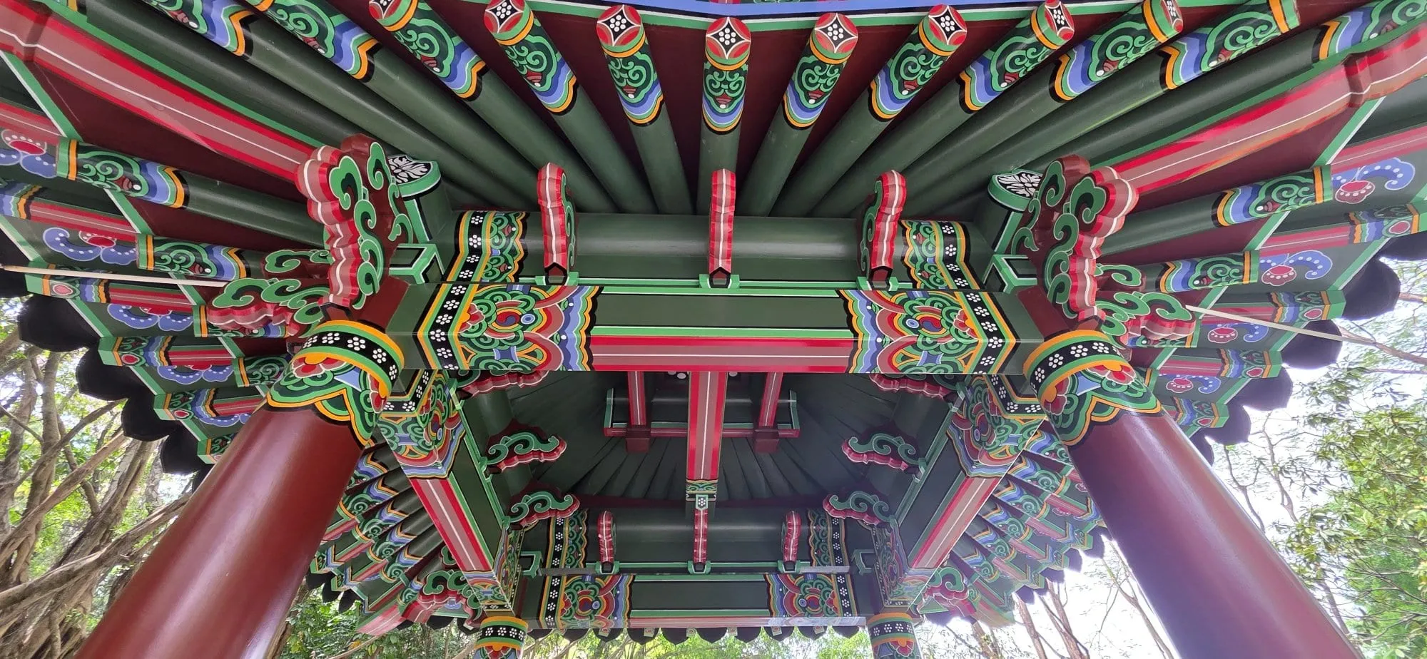 Un plafond traditionnel chinois peint de motifs verts, rouges et dorés