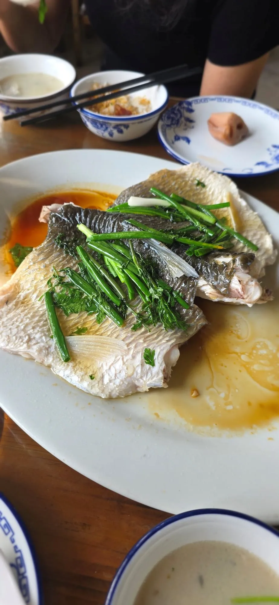 Un poisson entier cuit à la vapeur avec des herbes, dans une assiette de campagne