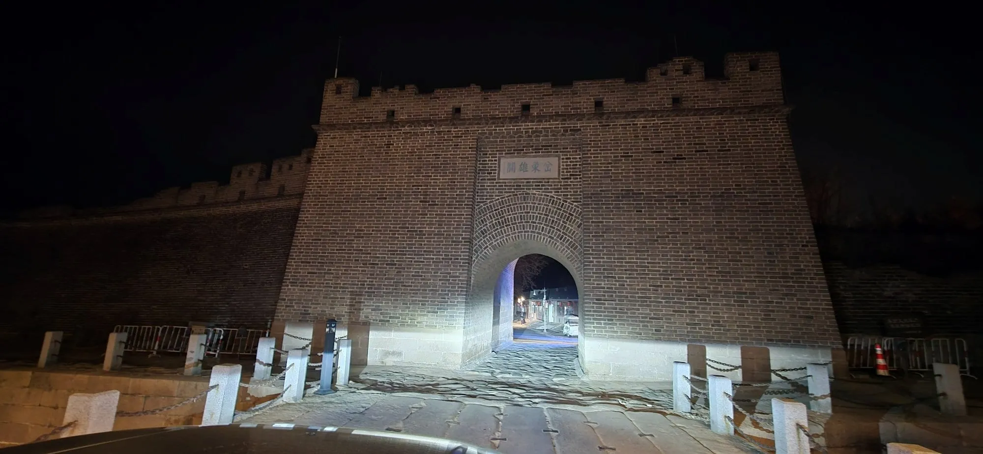 Une porte de ville fortifiée en pierre, éclairée de nuit, sans aucun visiteur