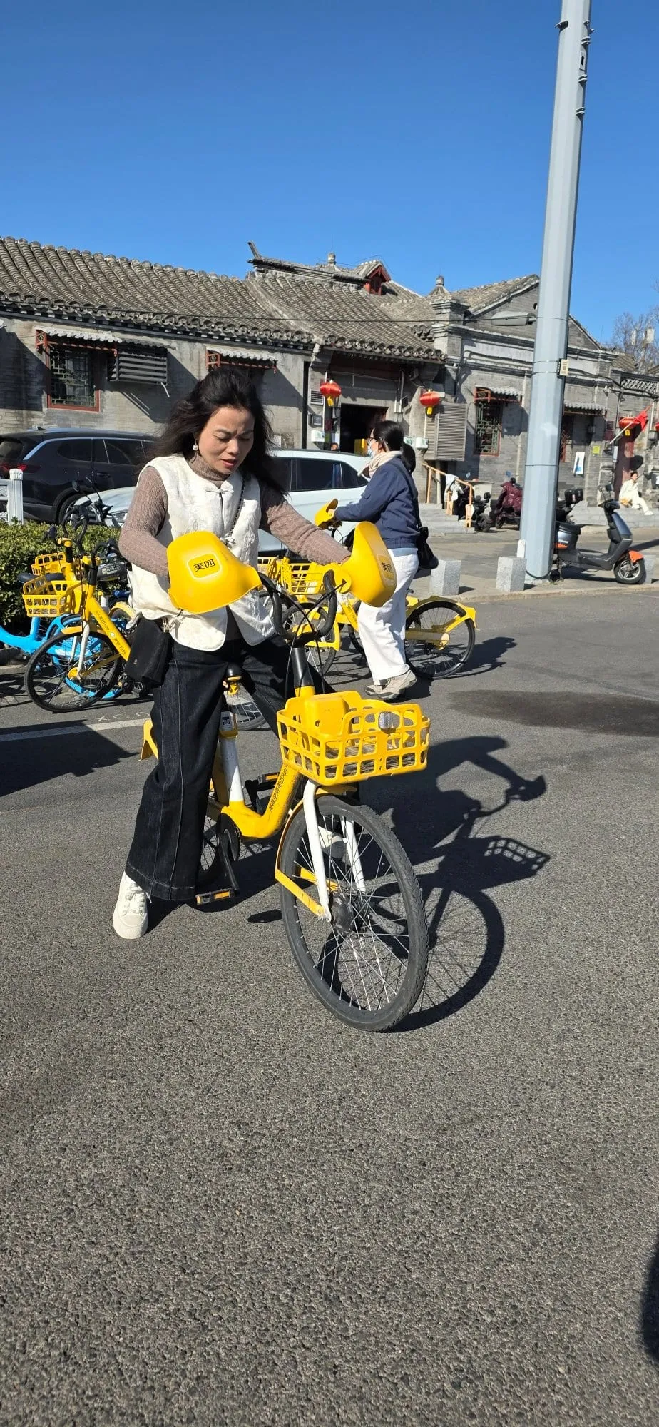 Une personne roulant sur un vélo jaune en libre-service, dans une rue de Pékin