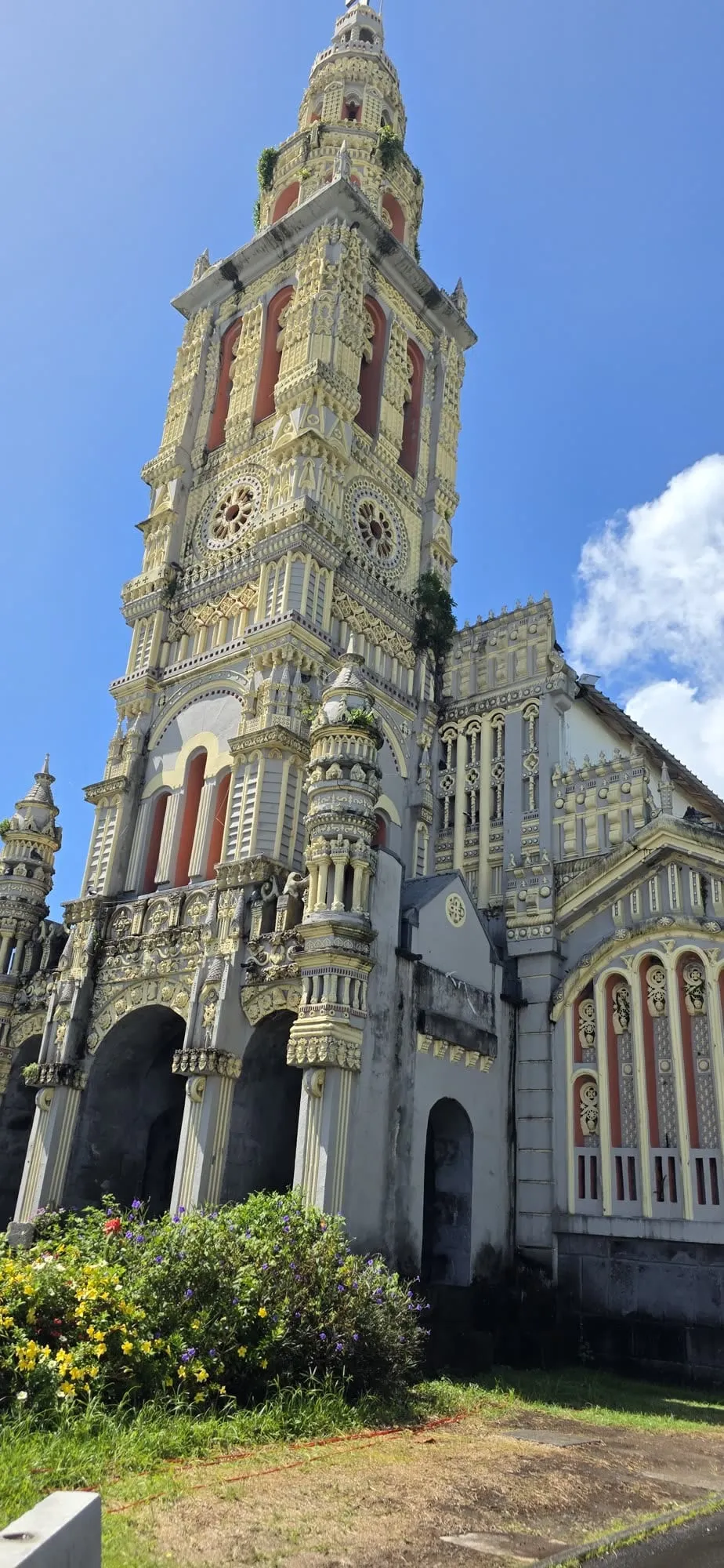 La façade d'une église entièrement sculptée de motifs clairs, une voiture au premier plan