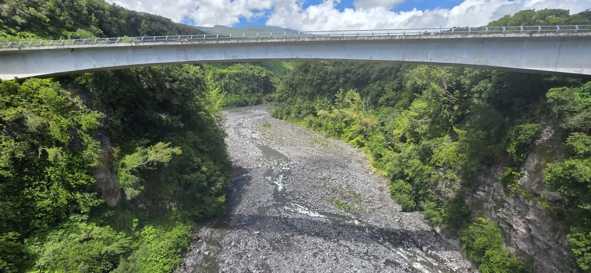 Un pont routier fin enjambant une rivière à galets, vu en plongée depuis un tablier