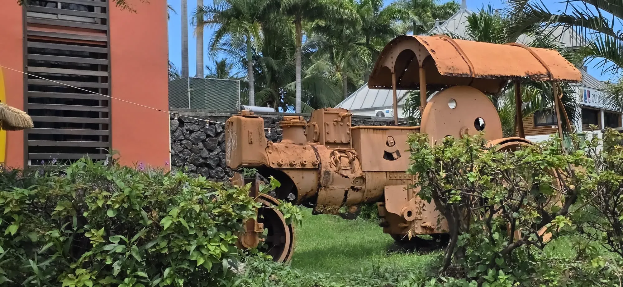 Une ancienne machine agricole rouillée exposée dans un jardin public côtier