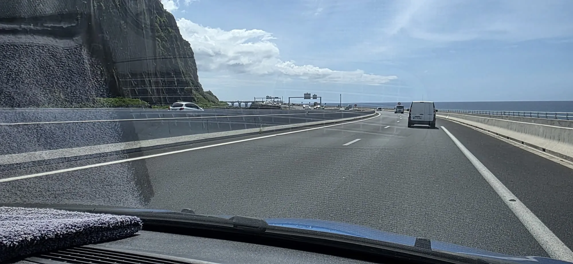 Un viaduc routier filant au-dessus de l'océan le long d'une falaise, vu du pare-brise