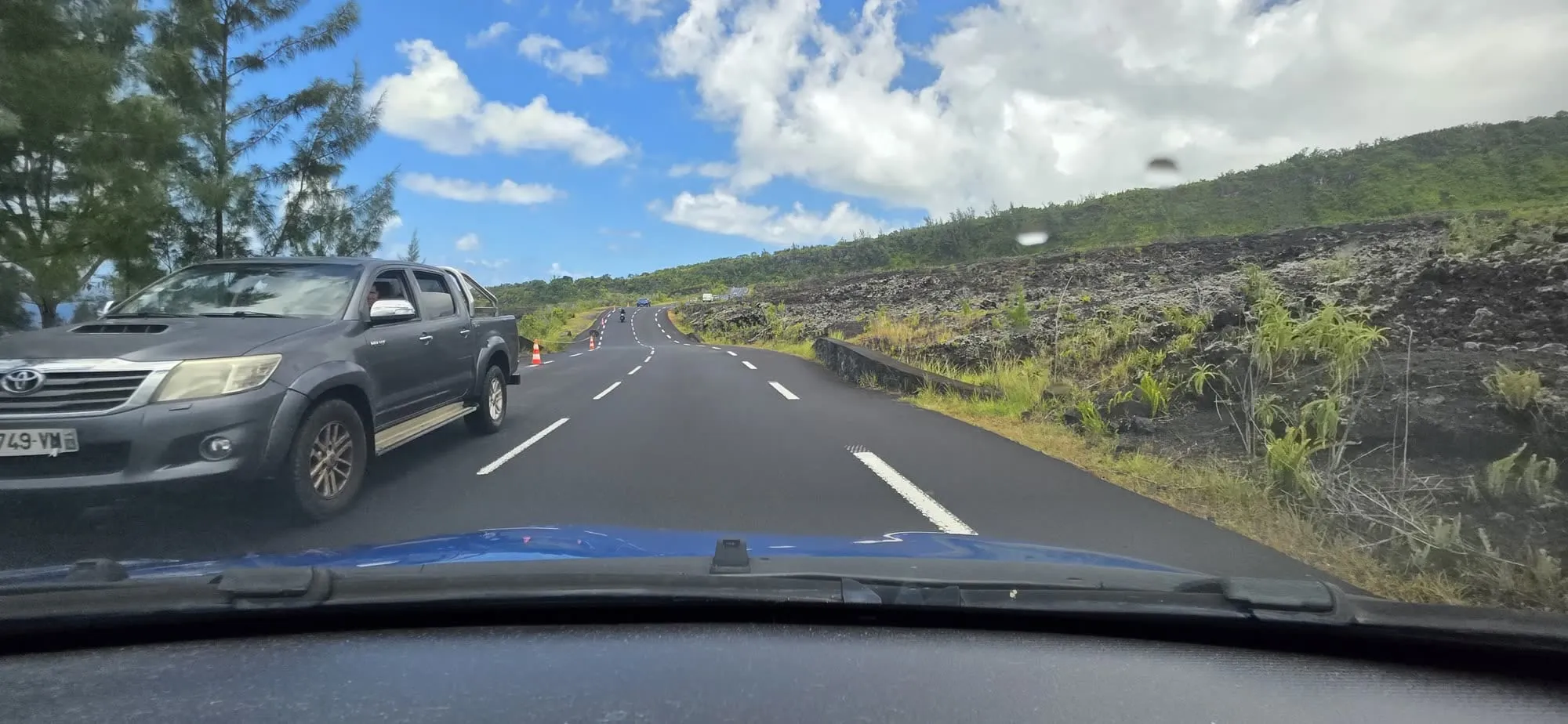 La route traversant une coulée de lave noire, vue depuis le pare-brise d'une voiture