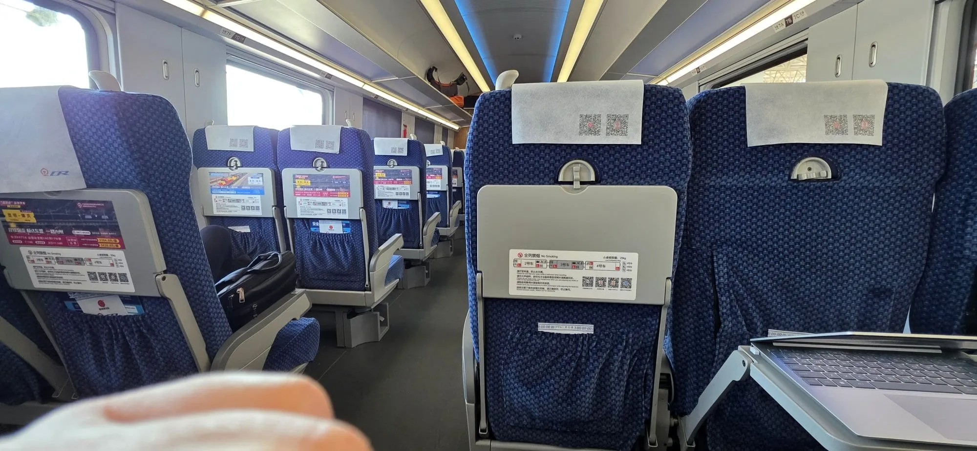 Intérieur d'une voiture de train à grande vitesse chinois, sièges bleus vides et tablettes rabattues