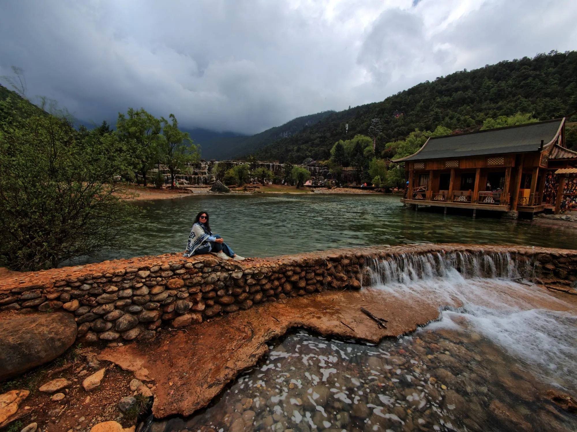 Une cascade en escalier sur des vasques de calcaire, avec un pavillon de bois en arrière-plan