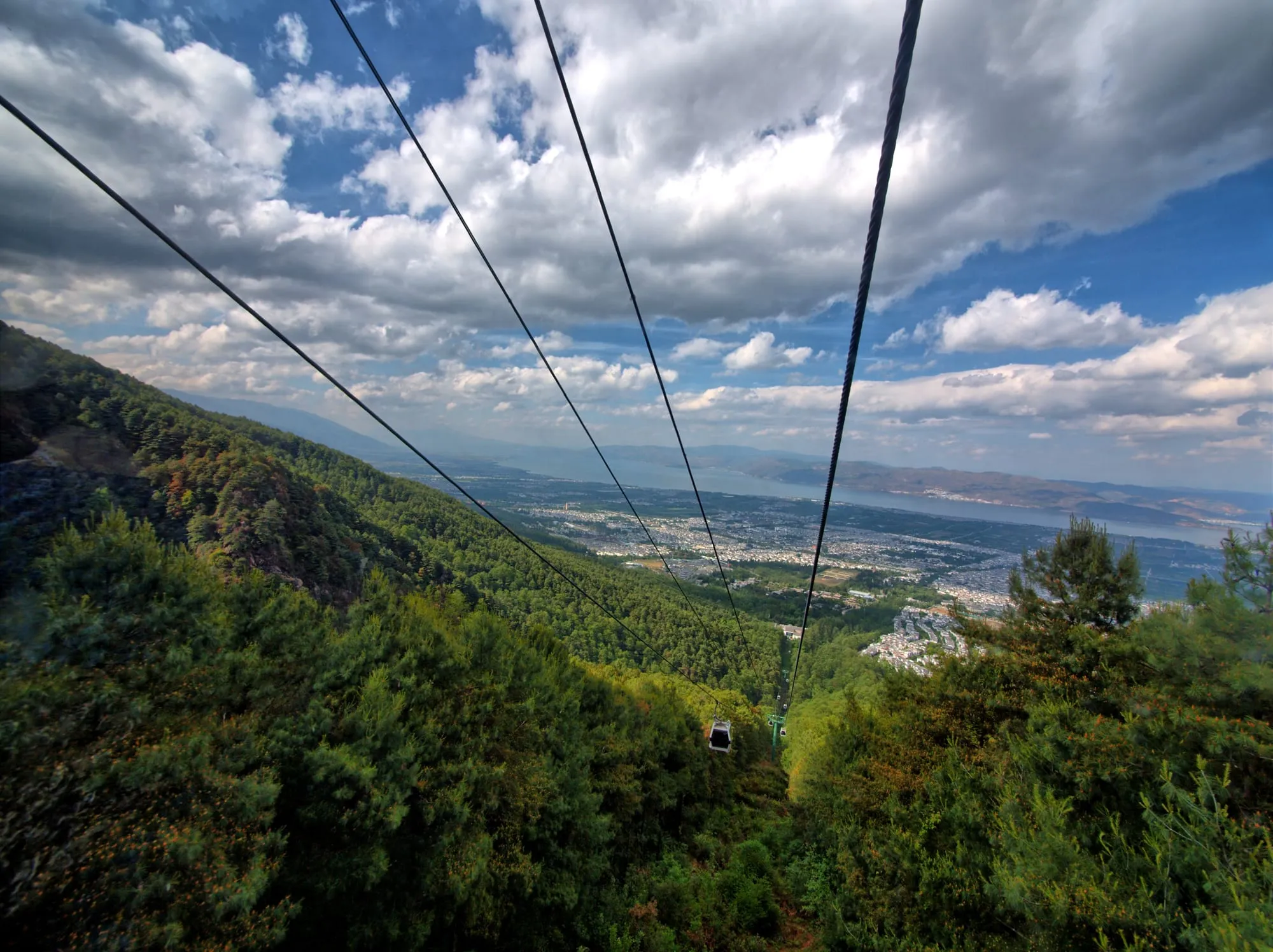 Vue depuis une cabine de téléphérique descendant au-dessus d'une vallée boisée du Cangshan