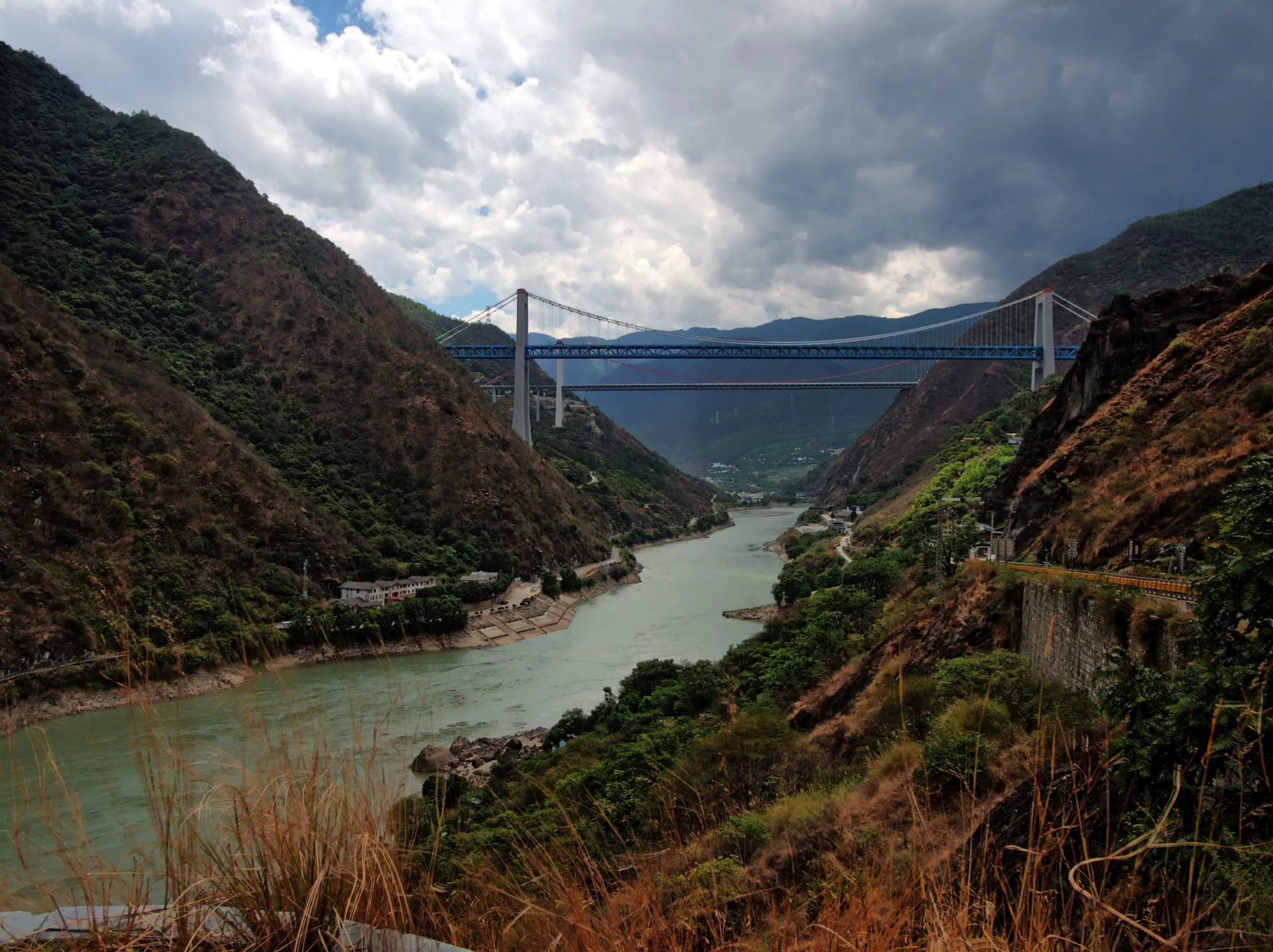 Une gorge encaissée avec un fleuve au fond et un pont suspendu très haut entre les deux versants